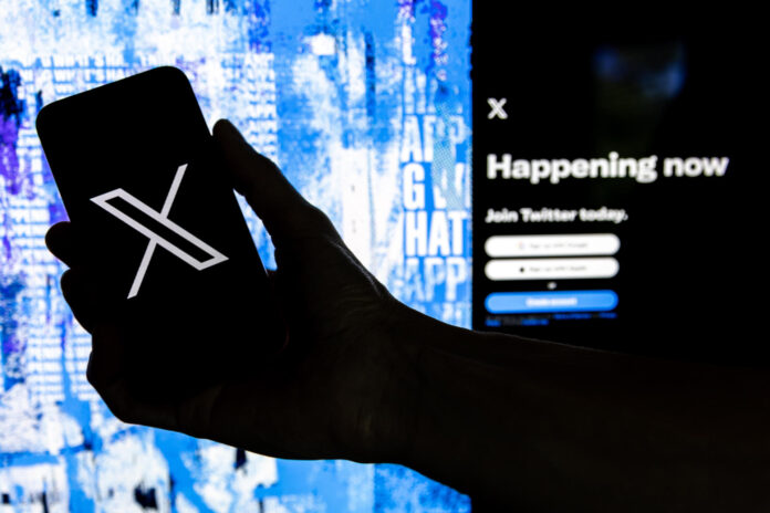 Imagen de archivo del 27 de julio de 2022, en la que puede verse a un usuario mientras sostiene un teléfono móvil que muestra el logotipo de la red social X. EFE/Etienne Laurent
