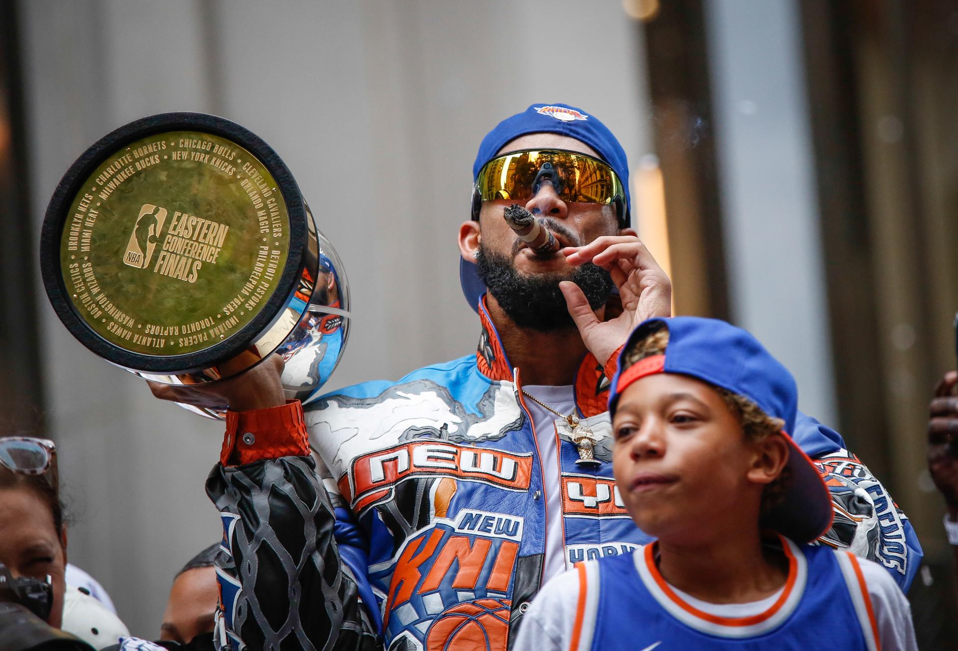 Karl-Anthony Towns, de los New York Knicks, fuma un cigarro sobre una carroza durante el desfile de cinta al ganador y mitin de victoria, celebrando su triunfo en las Finales de la NBA 2026 en Nueva York (Estados Unidos). EFE/KENA BETANCUR