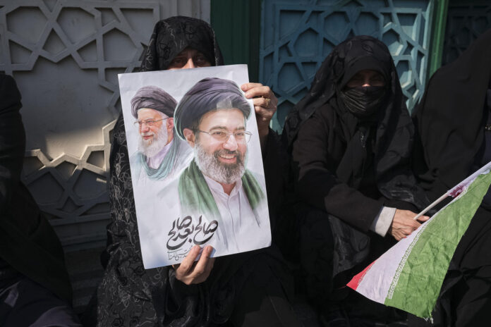 FOTO ARCHIVO.- Un mujer porta una pancarta con la imagen del nuevo líder supremo de Irán, Mojtaba Jameneí, y su padre y antecesor en el cargo, Alí Jameneí, durante los funerales Consejo Supremo de Seguridad Nacional, Ali Lariyani, en la plaza Enghelab de Teherán. Miles de personas despidieron este miércoles a Alí Lariyani, uno de los políticos más importantes del país persa y quien fue asesinado por Israel, entre llamadas a la venganza y a seguir luchando hasta la 