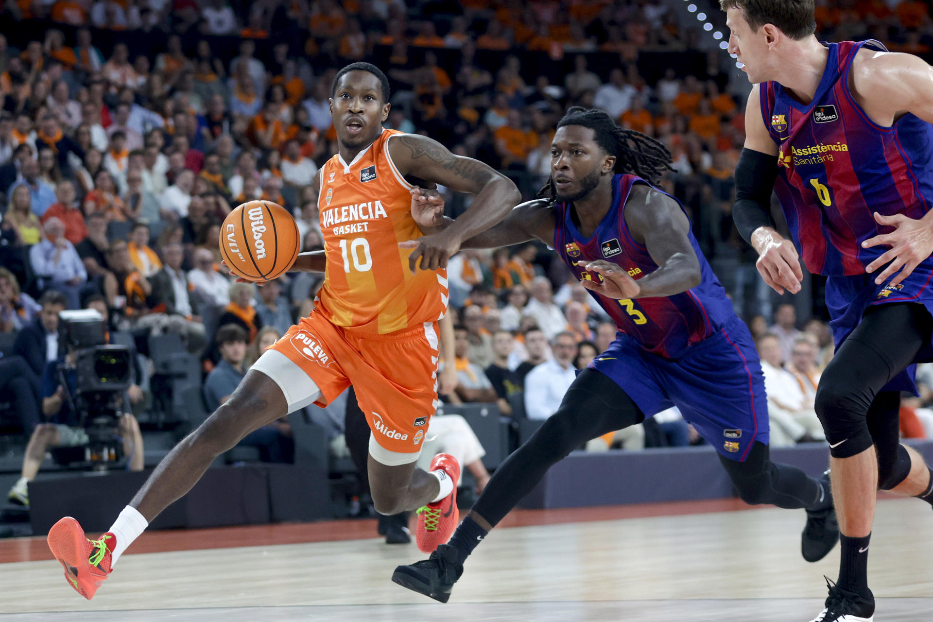 El alero del Valencia Omari Moore (i) juega un balón ante Myles Cale (c), del Barça, durante el primer partido de la final de la Liga Endesa de baloncesto que Valencia Basket y Barcelona disputan este jueves en el pabellón Roig Arena. EFE/Miguel Ángel Polo

