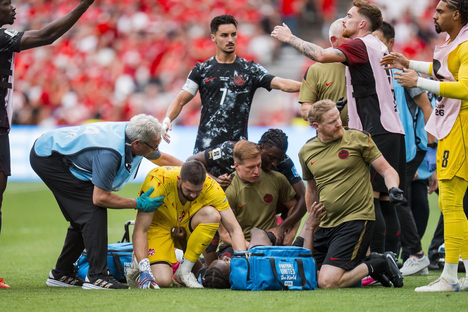 El guardameta canadiense Maxime Crepeau auxilia a su compañero, el mediocentro Ismael Koné, quien yace tendido en el césped del estadio de Vancouver tras sufrir una escalofriante lesión durante el partido contra Catar. EFE/EPA/BOB FRID
