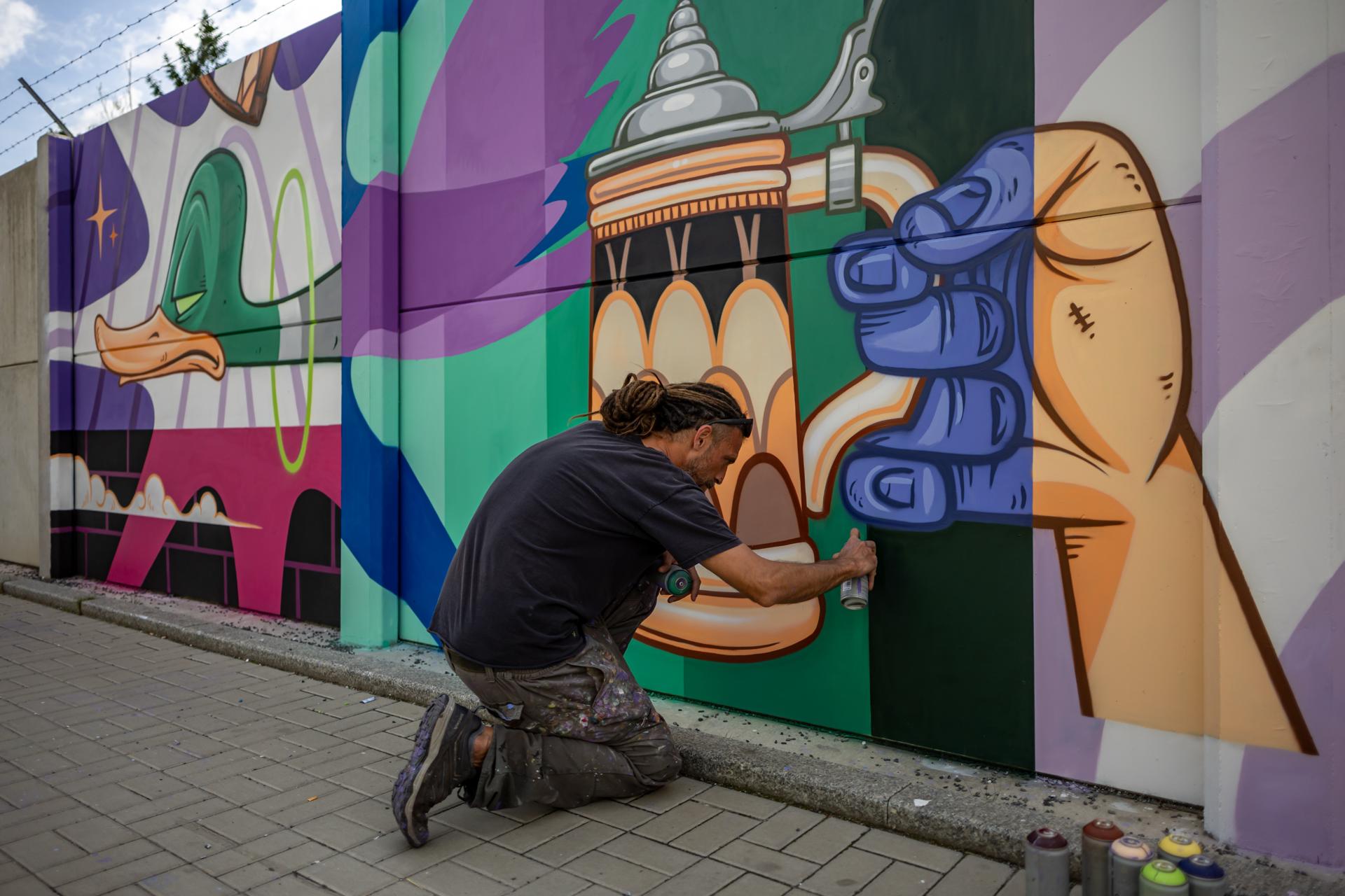 El artista español Marc Altafulla, conocido como Kram, crea una pintura de grafiti a gran escala durante el proyecto 'Mural Ruzyne' en Praga, República Checa, el 18 de junio de 2026 (emitido el 19 de junio de 2026). Este proyecto forma parte del festival Urban Pictus, que se celebra del 15 al 30 de junio y presenta 30 obras de destacados artistas callejeros checos e internacionales. Al cubrir un muro de hormigón de más de 700 metros de largo, se convertirá en el tercer mural más largo de este tipo en Europa una vez finalizado. EFE/EPA/MARTIN DIVISEK

