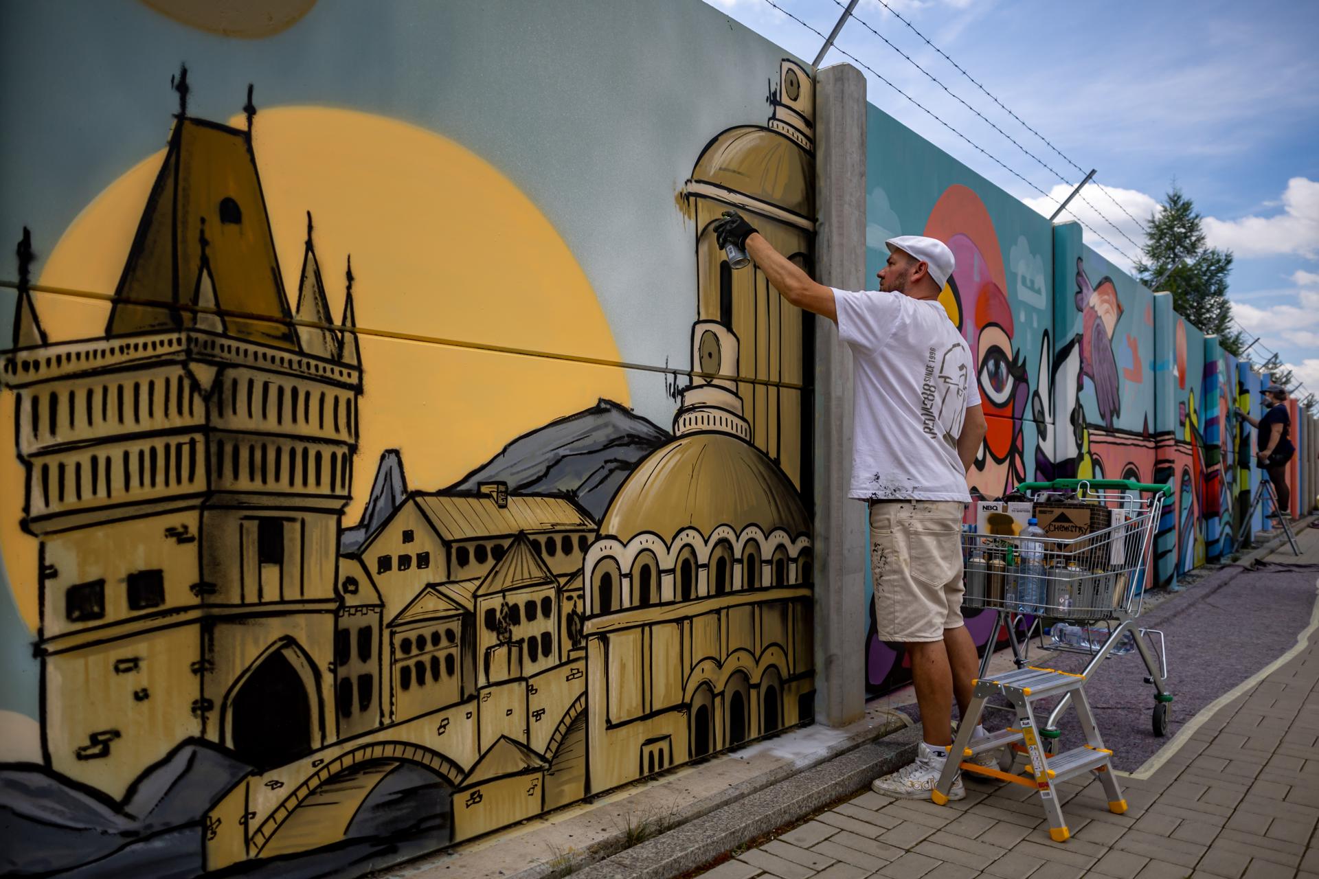 El artista polaco Maciej Kreda crea una pintura de gran escala durante el proyecto 'Mural Ruzyne' en Praga, República Checa, el 18 de junio de 2026 (emitido el 19 de junio de 2026). Este proyecto forma parte del festival Urban Pictus, que se desarrolla del 15 al 30 de junio, con 30 obras de destacados artistas callejeros checos e internacionales. Cubriendo un muro de hormigón de más de 700 metros de largo, se convertirá en el tercer mural más largo de su tipo en Europa una vez finalizado. EFE/EPA/MARTIN DIVISEK
