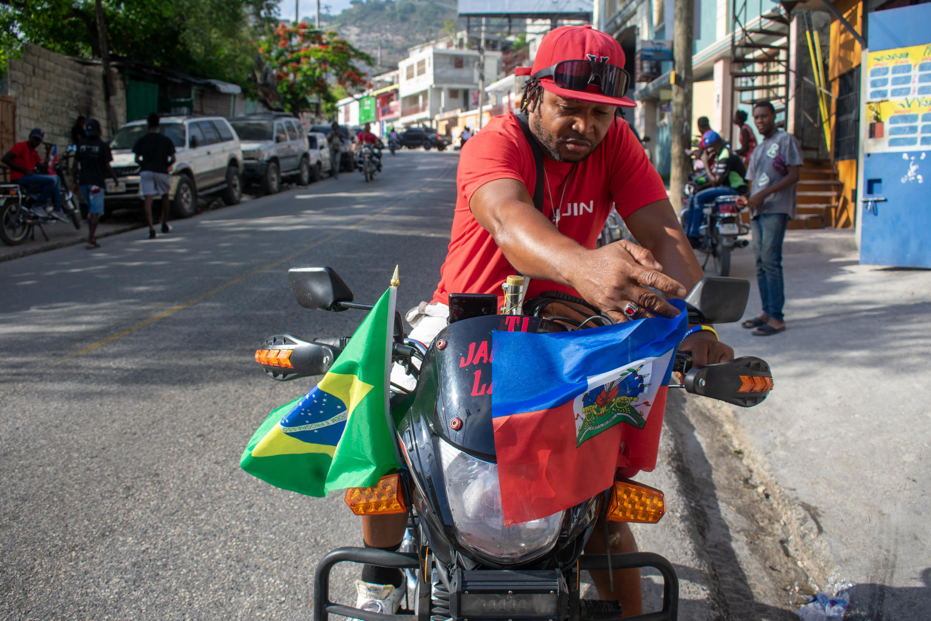 Una persona transita en una motocicleta decorada con banderas de Haití y Brasil, en Puerto Príncipe (Haití). EFE/ Jonet St Élois