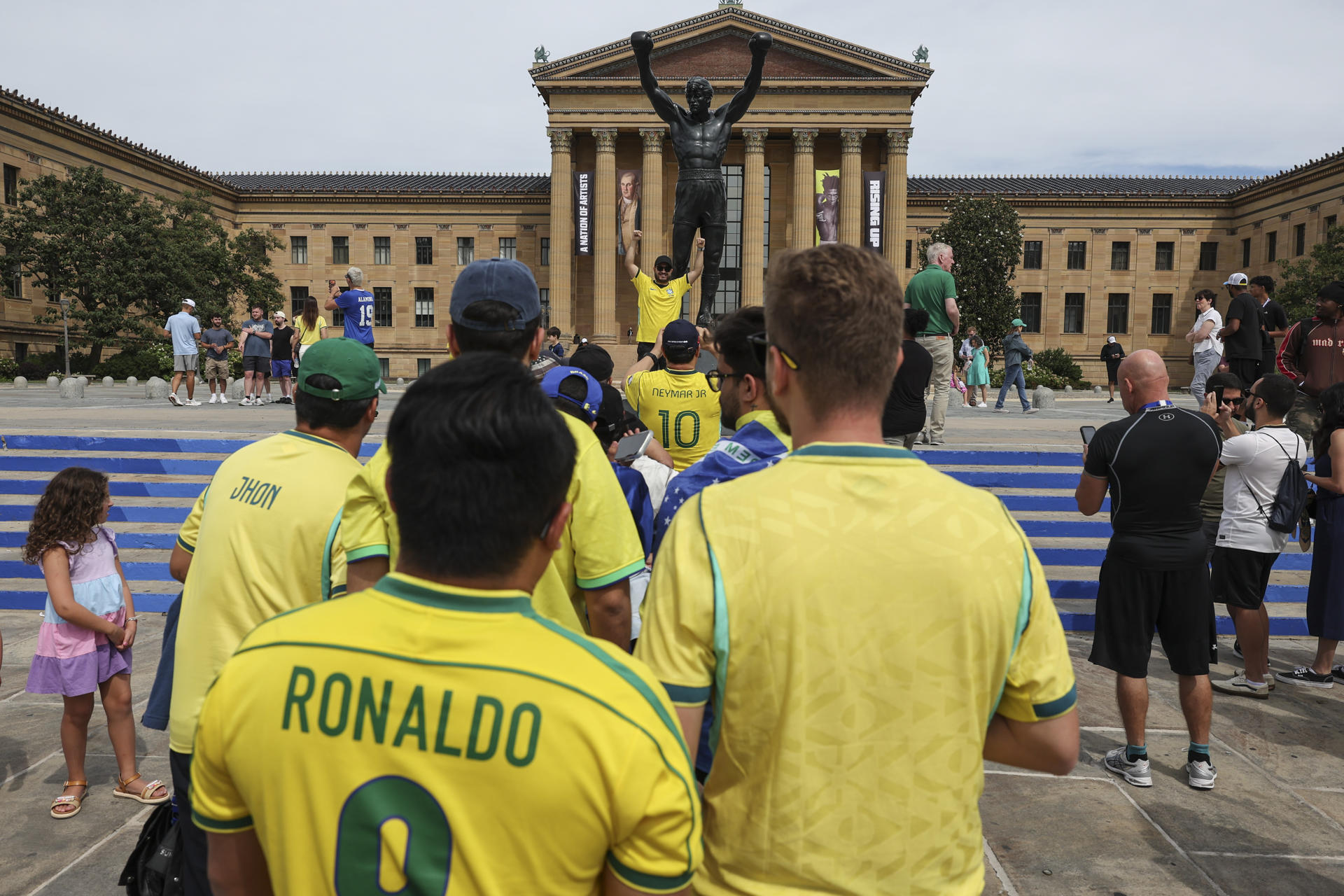 Los aficionados de la selección brasileña de fútbol visitan la estatua del boxeador Rocky Balboa en el centro de Filadelfia (EE.UU.), inspirada en el personaje interpretado por Sylvester Stallone en las películas. EFE/SEBASTIÃO MOREIRA
