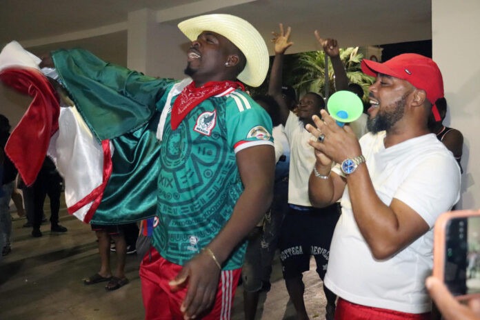 El migrante de Haití, Seña Tus Roodson (i), observa la transmisión del partido del Mundial de la FIFA 2026 entre México y Corea del Sur este jueves, en la ciudad de Tapachula (México). EFE/Juan Manuel Blanco

