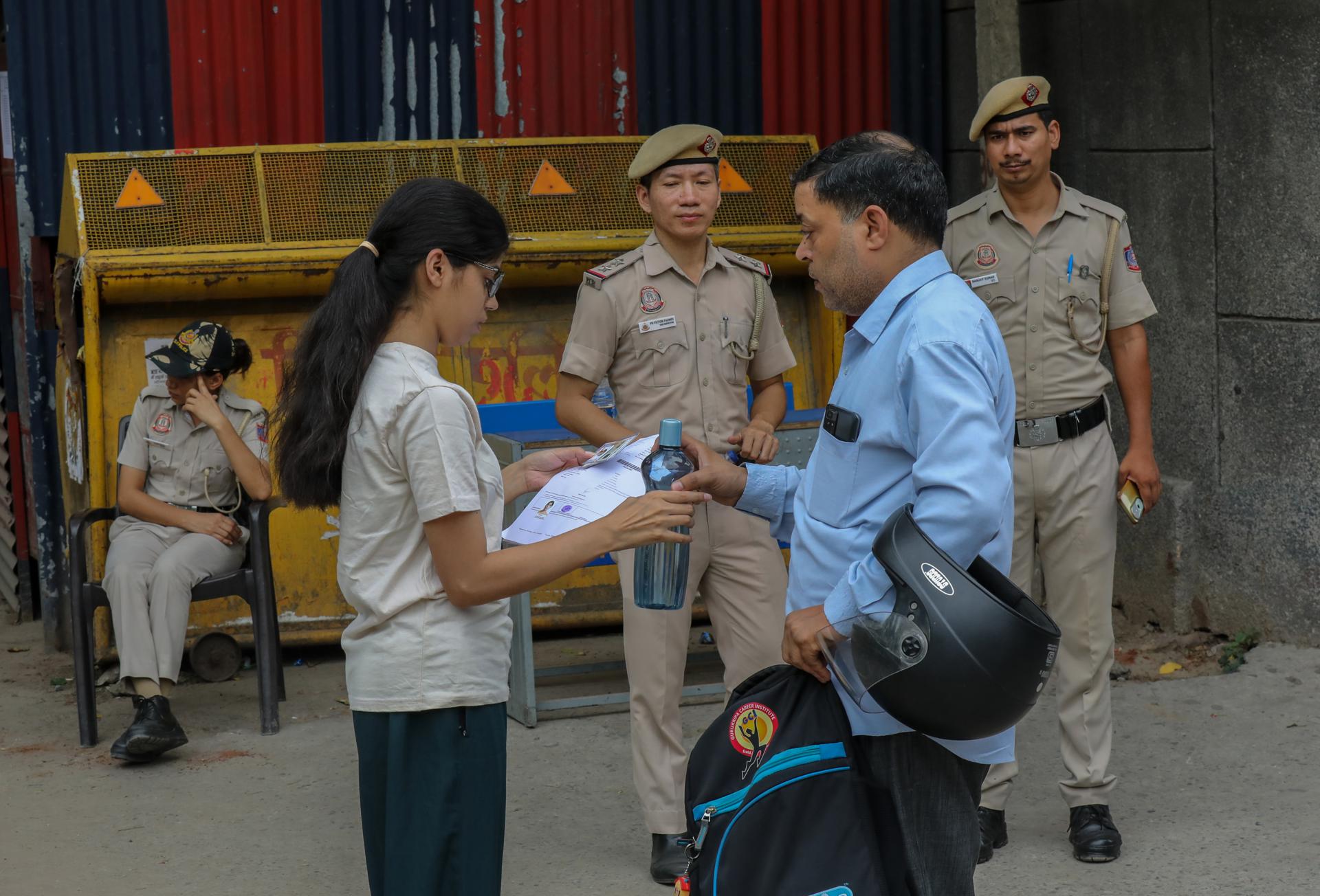 Agentes de seguridad vigilan mientras una estudiante llega para hacer el examen médico NEET-UG en un centro de Nueva Delhi, India, el 21 de junio de 2026. Los aspirantes a ingresar en programas de grado en medicina realizan hoy una repetición del examen NEET-UG después de que la Agencia Nacional de Pruebas de India (NTA) anulara la prueba celebrada el 3 de mayo en el marco de una investigación por presuntos filtraciones del examen (Nueva Delhi) EFE/EPA/RAJAT GUPTA