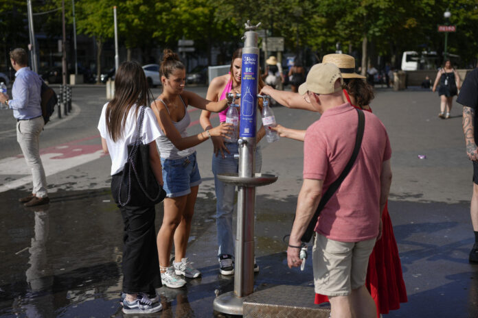 Grupos de personas se hidratan en una fuente este martes en París. EFE/ Edgar Sapiña Manchado
