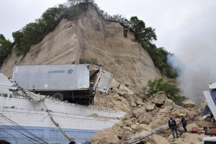 Integrantes del Cuerpo de Bomberos de Honduras atienden el derrumbe de un cerro sobre una bodega en Tegucigalpa (Honduras). EFE/ STR
