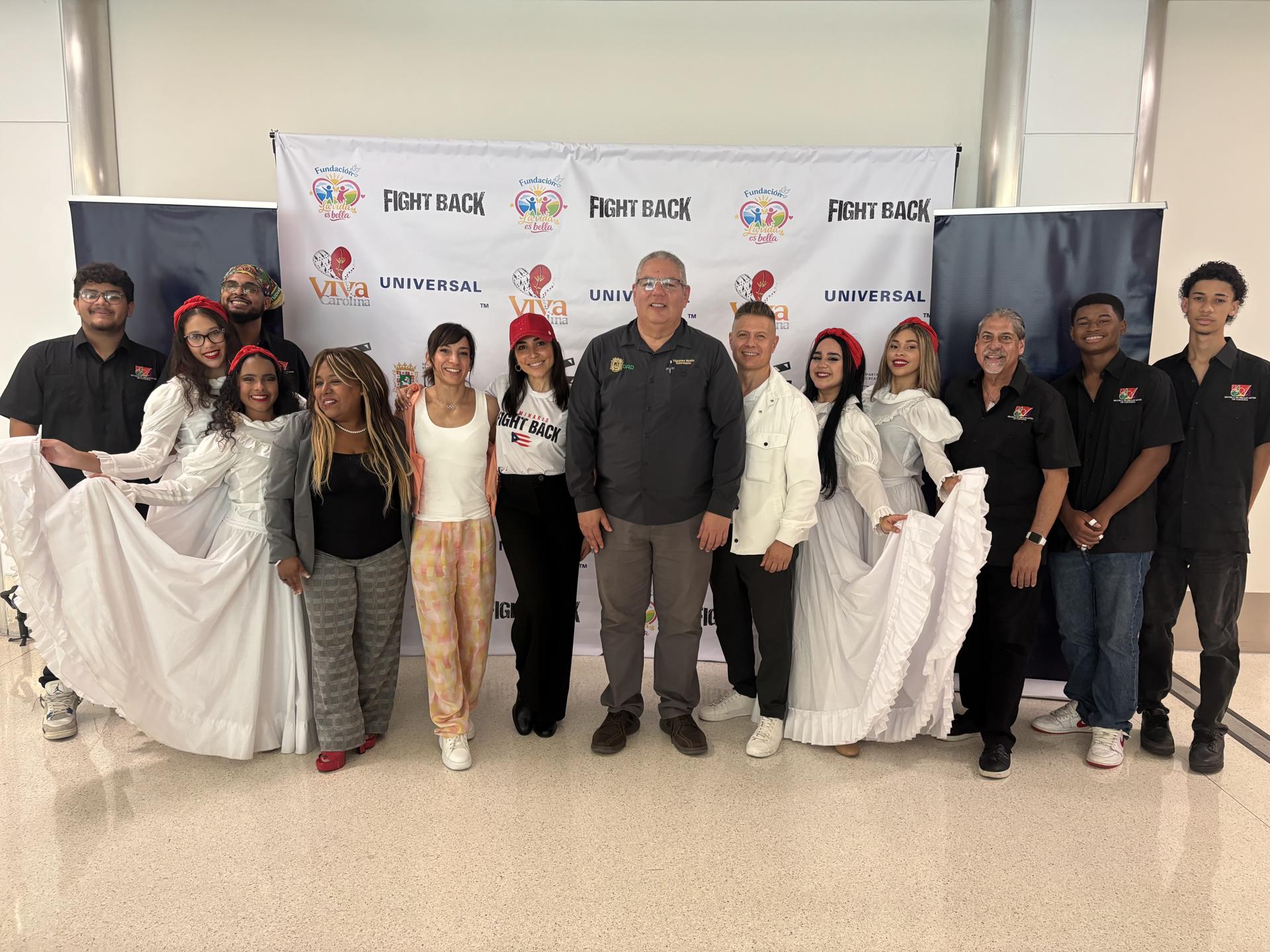 Fotografía del 18 de junio de 2026 que muestra a la actriz y cantante puertorriqueña, Ana Isabelle (6-i); a la karateka española Sandra Sánchez (5i), a su esposo y entrenador Jesús del Moral (6d), posando con el secretario del Departamento de Recreación y Deportes (DRD) de Puerto Rico, Héctor Vázquez (c), y los miembros de la agrupación del género musical de bomba de la escuela de Bellas Artes en Carolina (Puerto Rico). EFE/ Esther Alaejos
