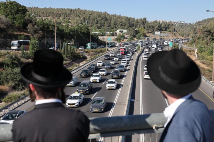 Dos judíos ultraortodoxos observan la protesta que esta comunidad religiosa ha realizado en las carreteras de entrada a Jerusalén. EFE/EPA/ABIR SULTAN EPA
