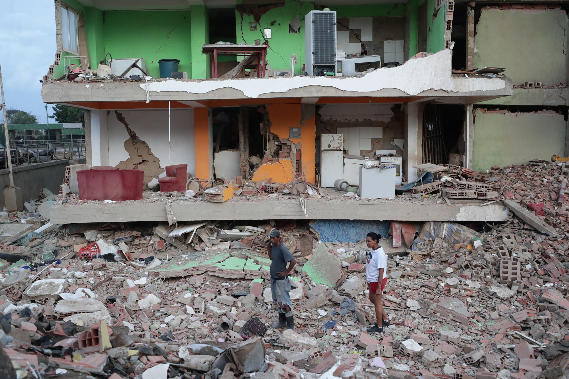 Dos residentes entre los escombros de uno de los bloques de viviendas derrumbado por los terremotos en la localidad de Catia La Mar, en el estado costero de La Guaira (Venezuela) este jueves.  EFE/ Ronald Pena R.
