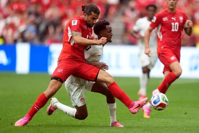 Ricardo Rodríguez, de Suiza (a la izquierda), y Ali Ahmed, de Canadá, en acción durante el partido de la fase de grupos del Mundial de la FIFA. EFE/EPA/BOB FRID
