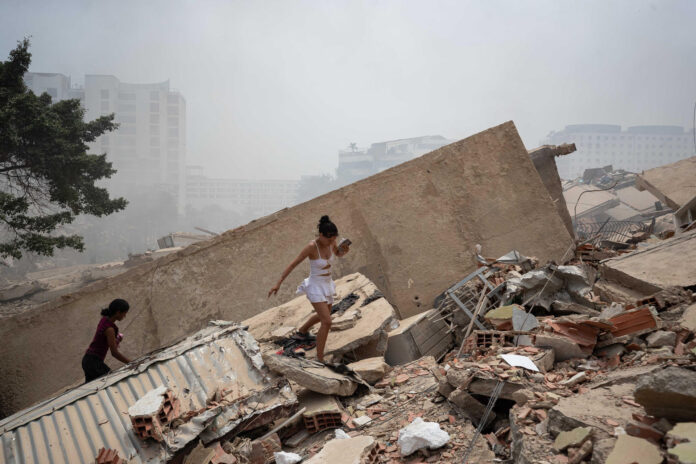 Personas caminan este jueves, entre los escombros de edificios afectados por los terremotos en La Guaira (Venezuela). EFE/ Ronald Peña R.
