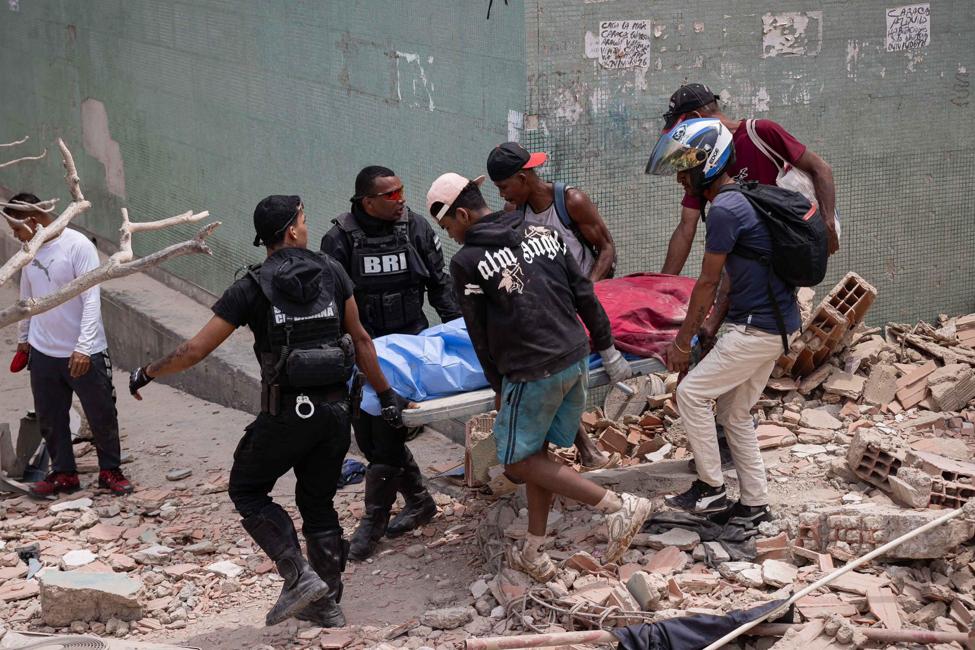 Voluntarios fueron captados este 25 de julio al rescatar una víctima mortal, entre los escombros de edificios afectados por los terremotos, en La Guaira (Venezuela). EFE/Ronald Peña
