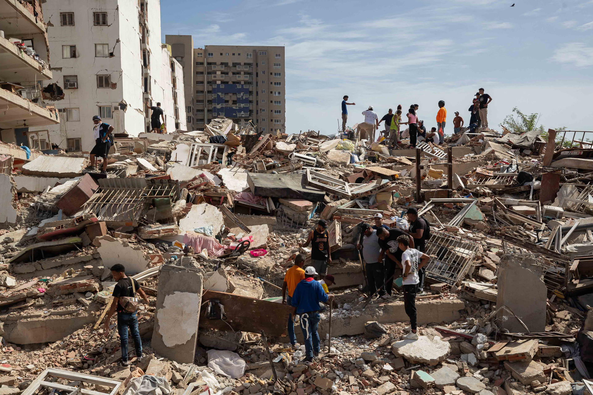 Personas caminan entre escombros de edificios afectado por terremotos este jueves, en Catia La Mar (Venezuela). EFE/ Ronald Peña R.
