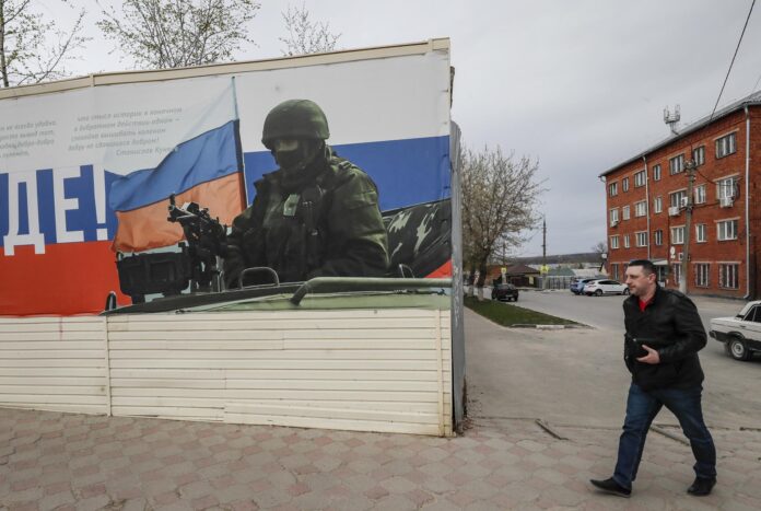 Foto de archivo de la localidad rusa de Yefremov, en la región de Tula, una de las más afectadas por los ataques de este viernes, en la que un hombre pasa frente a un cartel que representa a un militar ruso armado. EFE/EPA/YURI KOCHETKOV
