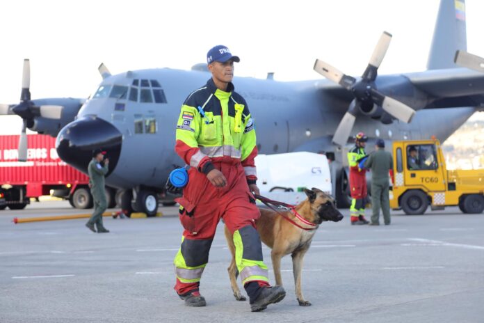Un bombero camina con un perro preparándose para viajar a Venezuela este jueves desde la ciudad de Latacunga (Ecuador). EFE/Diego Paredes
