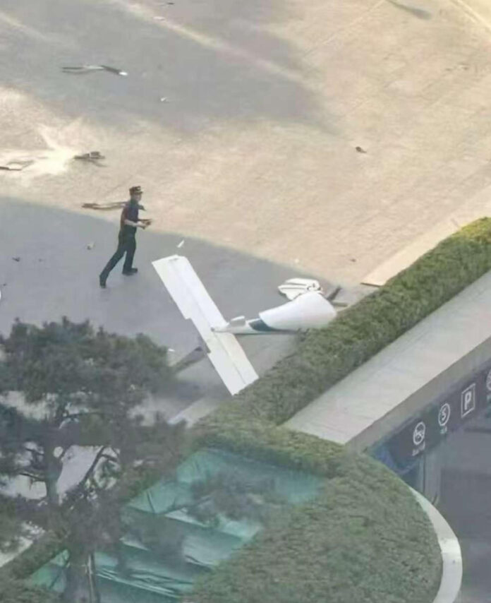 . PEKÍN (CHINA), 26/06/2026.- Fotografía cedida que muestra un integrante de la Policía de China frente a un fragmento de una aeronave en una vía próxima al edificio China Zun este viernes, en Pekin (China). Una avioneta se estrelló en Pekín contra el edificio más alto de la capital china, confirmaron testigos a EFE, sin que por el momento se conozcan las causas del suceso. EFE/ Cortesía
