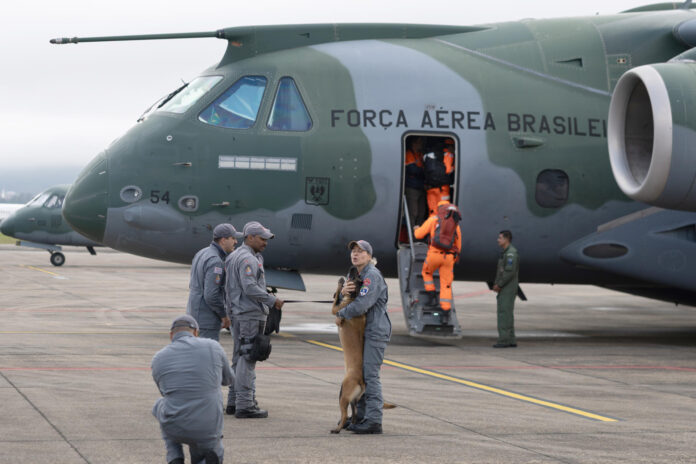 Fotografía que muestra a una integrante de la Policía Militar saludando a un canino antes de abordar un avión este viernes, en la Base Aérea de São Paulo, en Guarulhos (Brasil). EFE/ Isaac Fontana
