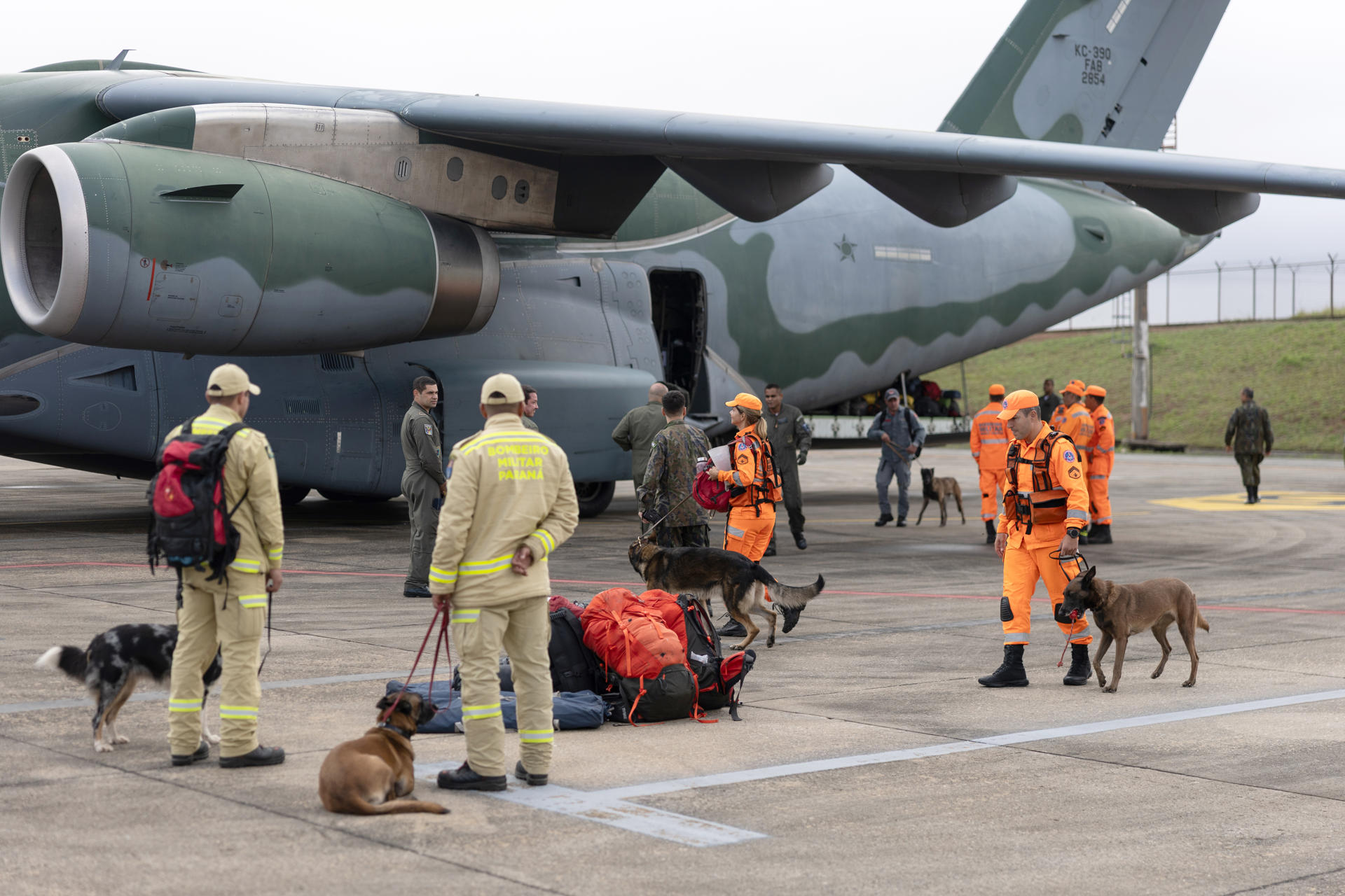 Fotografía que muestra a integrantes de Bomberos acompañados de caninos antes de abordar un avión militar este viernes, en la Base Aérea de São Paulo, en Guarulhos (Brasil). EFE/ Isaac Fontana
