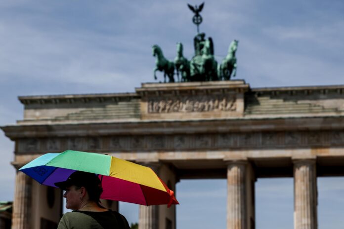 Un turista se protege del sol bajo una sombrilla en frente de la puerta de Brandenburgo in Berlin el 27 de junio de 2026.EFE/EPA/FILIP SINGER
