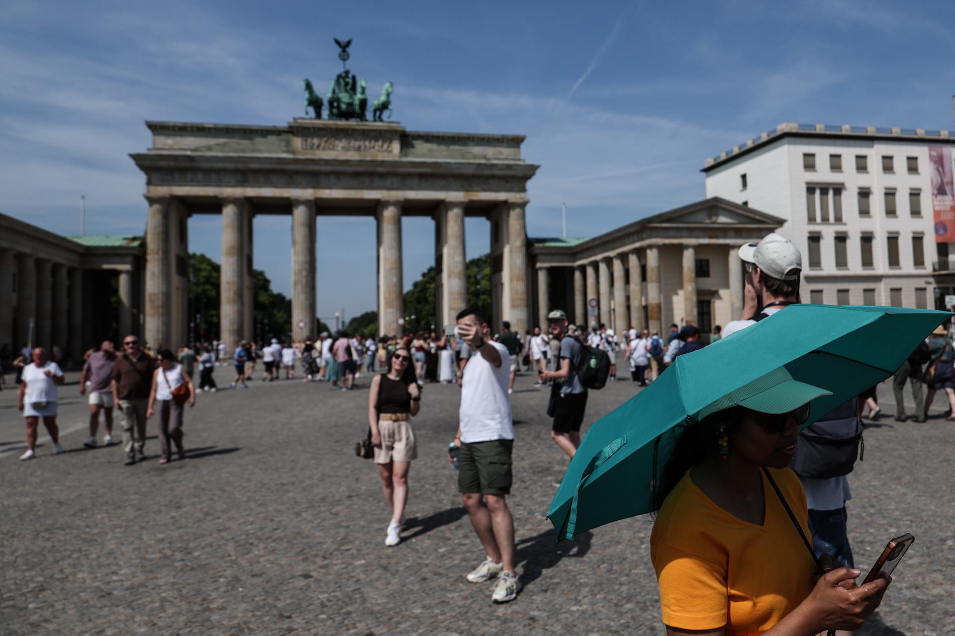 Un turista se protege del sol bajo una sombrilla en frente de la puerta de Brandenburgo in Berlin el 27 de junio de 2026.EFE/EPA/FILIP SINGER
