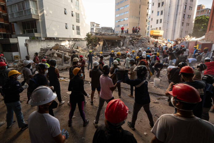 Decenas de personas fueron captadas este 27 de junio al realizar labores de rescate y remoción de escombros, en una zona afectada por los terremotos del pasado sábado, en Caracas (Venezuela). EFE/Ronald Peña
