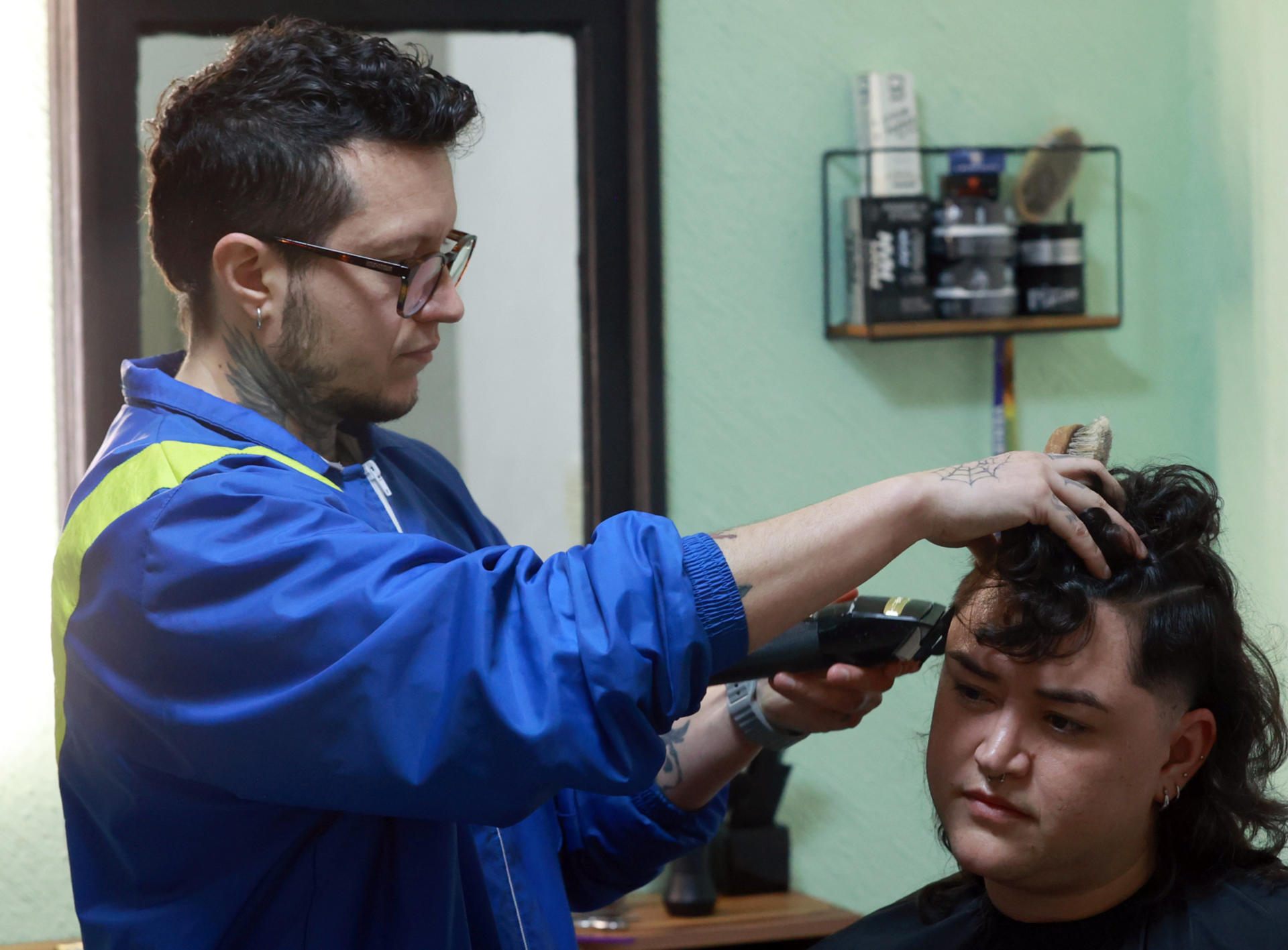 El estilista León Castillo (i) corta el cabello a una persona este sábado, en su barbería 'Diablites Klub' de Ciudad de México (México). EFE/ Mario Guzmán
