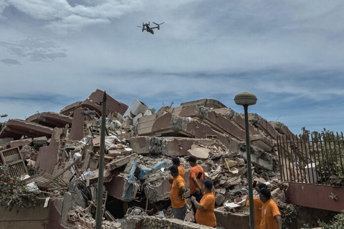 Personas observan un dron durante operaciones de rescate en una zona afectada por los terremotos, este domingo, en La Guaira (Venezuela). EFE/ Henry Chirinos
