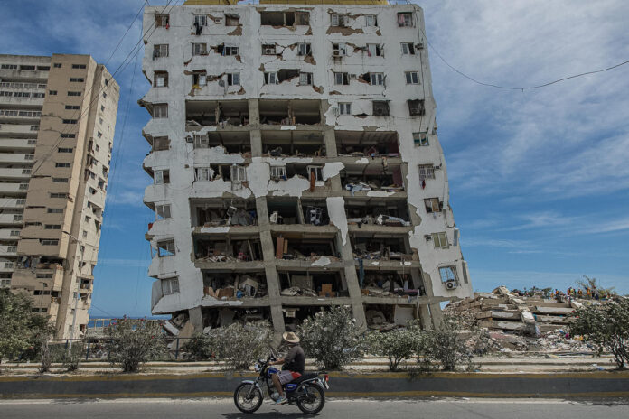 Una persona transita frente a un edificio destruido por los terremotos, este domingo, en Catia La Mar (Venezuela). EFE/ Henry Chirinos
