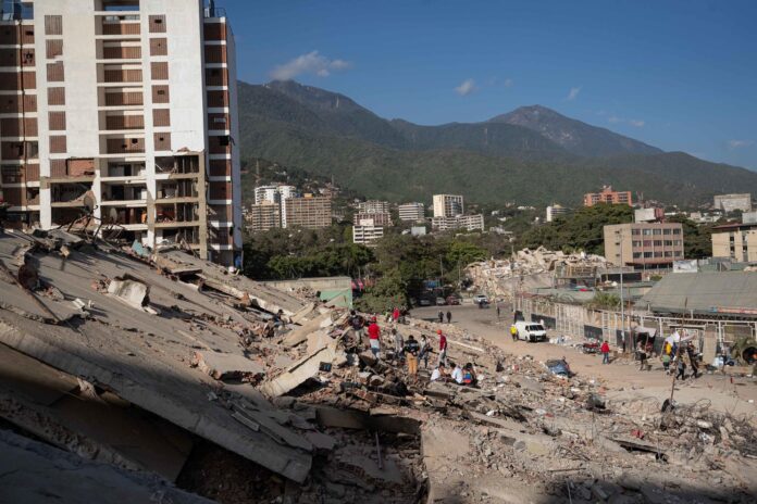 Personas observan los escombros de un edificio este lunes, en La Guaira (Venezuela). EFE/ Ronald Peña R
