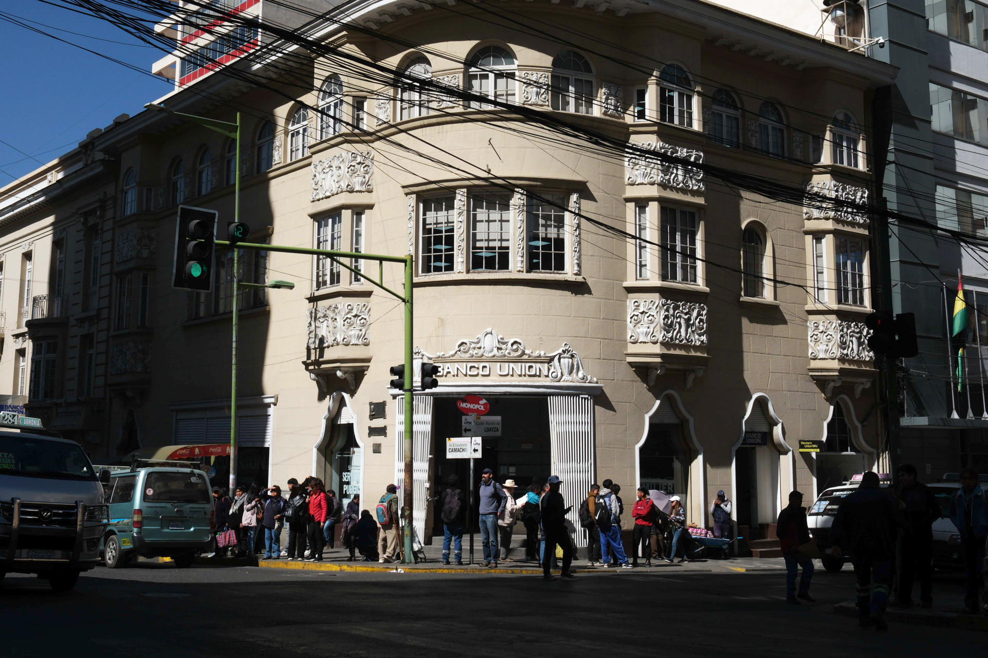 Personas caminan frente a un banco este lunes, en La Paz (Bolivia). EFE/Luis Gandarillas
