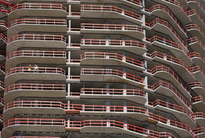Dos empleados de la construcción permanecen en uno de los balcones de la Grand Tower, el edificio residencial más alto de Alemania, en Fráncfort, en una imagen de archivo. EFE/ Mauritz Antin
