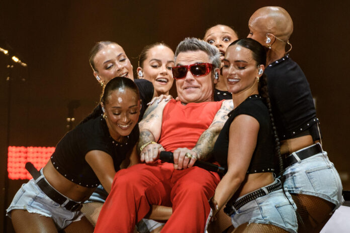 El cantante británico Robbie Williams (c) durante el concierto del Icónica Sevilla Fest ofrecido este martes en la Plaza de España, dentro de su gira 'Long 90's Tour', con la que también presenta su nuevo álbum, 'Britpop'. EFE/ Raúl Caro
