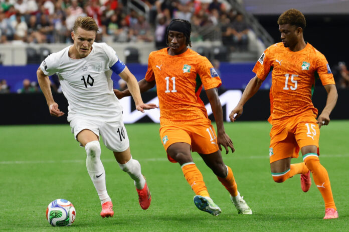 El centrocampista de Noruega Martin Odegaard (i) se lleva el balón ante el delantero de Costa de Marfil Yan Diomande (c) durante el partido de los dieciseisavos de final del Mundial 2026 que se disputó en Dallas, Texas (EE.UU.). EFE/Carlos Ramírez
