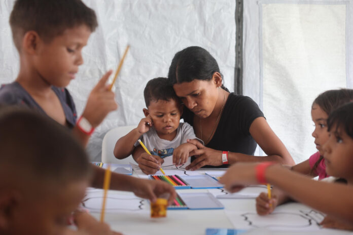 Una mujer dibuja junto a un niño en un polideportivo donde viven centenares de personas una semana después del doble terremoto de Venezuela, en La Guaira (Venezuela). EFE/ Miguel Gutiérrez
