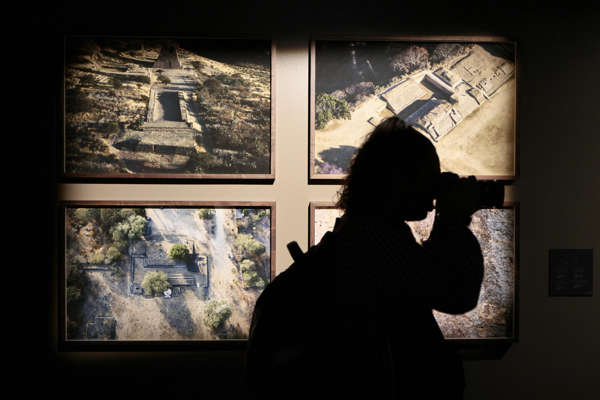 Una mujer toma una fotografía en la exposición fotográfica 'Tlachtli, espacios del juego sagrado' del mexicano Santiago Arau que propone una mirada contemporánea al ancestral juego de pelota mesoamericano, este jueves, en el Museo Nacional de Antropología de Ciudad de México (México). EFE/José Méndez