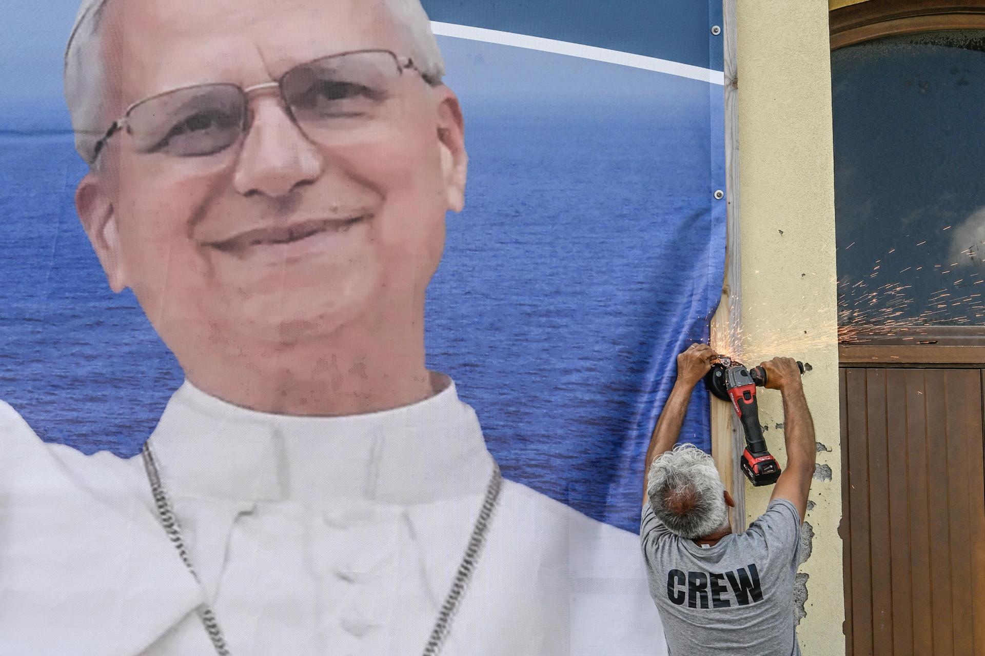 Un trabajador instala una enorme fotografía con motivo de la visita del papa León XIV a Lampedusa, Italia, el 3 de julio de 2026. León XIV visitará el 4 de julio la isla italiana. EFE/EPA/CIRO FUSCO
