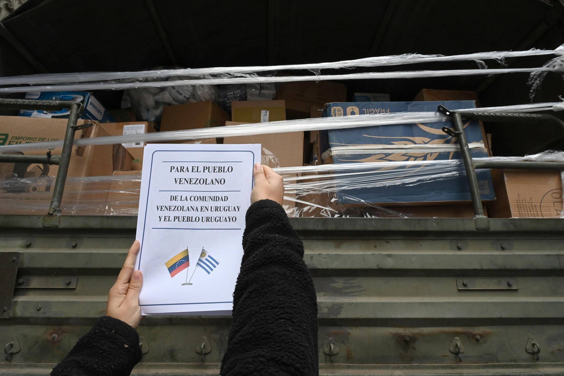Una persona pega un cartel en el camión que transporta productos recolectados por la comunidad venezolana y uruguaya este viernes en Montevideo (Uruguay). EFE/ Federico Gutiérrez
