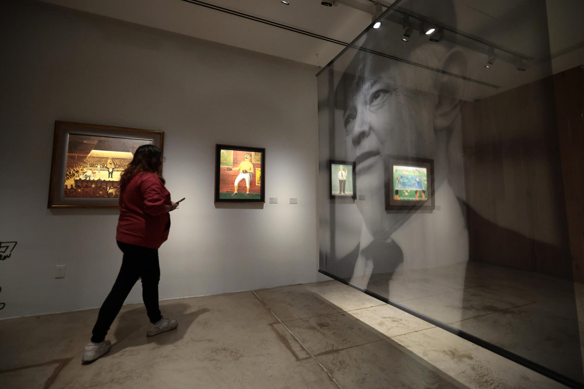 Una periodista recorre este viernes la exposición '¡México-México-México! Abel Quezada entre arte y deporte' que será inaugurada el próximo domingo en el Museo la luz, en Ciudad de México (México). EFE/José Méndez
