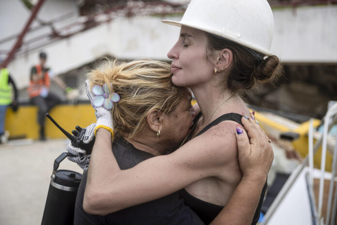 Una rescatista (d) fue captada este 3 de julio al abrazar a una mujer durante la jornada de búsqueda de sobrevivientes de los terremotos en Venezuela el pasado 24 de junio, en Caraballeda (La Guaira, Venezuela). EFE/Miguel Gutiérrez
