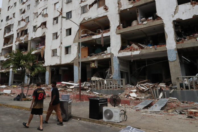 Personas caminan frente a edificios afectados por los terremotos ocurridos en la zona de Caraballeda, en La Guaira (Venezuela). EFE/ Raúl Martínez
