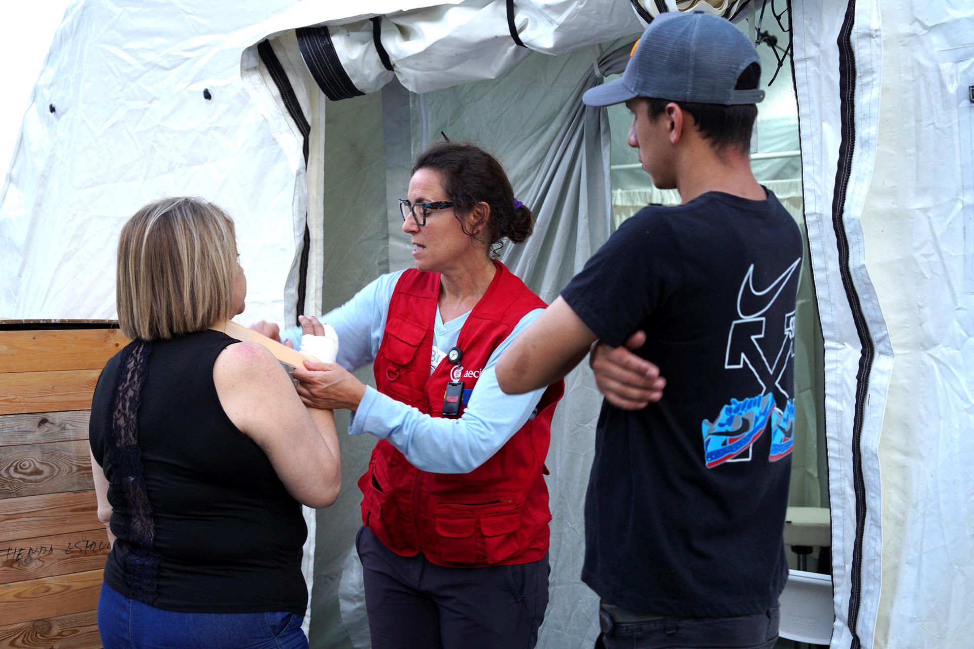 Fotografía cedida por la Agencia Española de Cooperación Internacional para el Desarrollo (AECID) que muestra a una voluntaria del grupo START (Equipo Técnico de Ayuda y Respuesta de Emergencia) coordinado por AECID (c) brindando atención a una persona durante la inauguración de un hospital este sábado, en Caracas (Venezuela).EFE/ AECID
