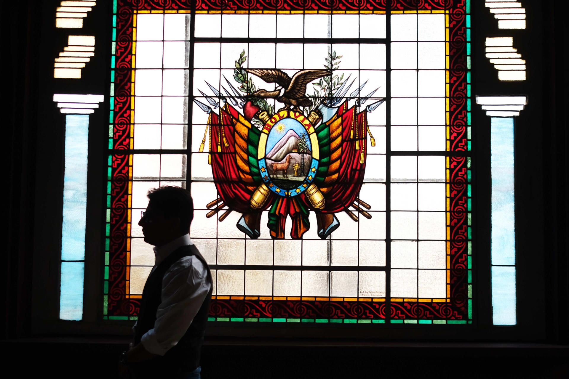 Una persona camina frente a un vitral con el escudo de Bolivia este jueves, en el Museo Nacional de Arqueología, en La Paz (Bolivia). EFE/ Luis Gandarillas
