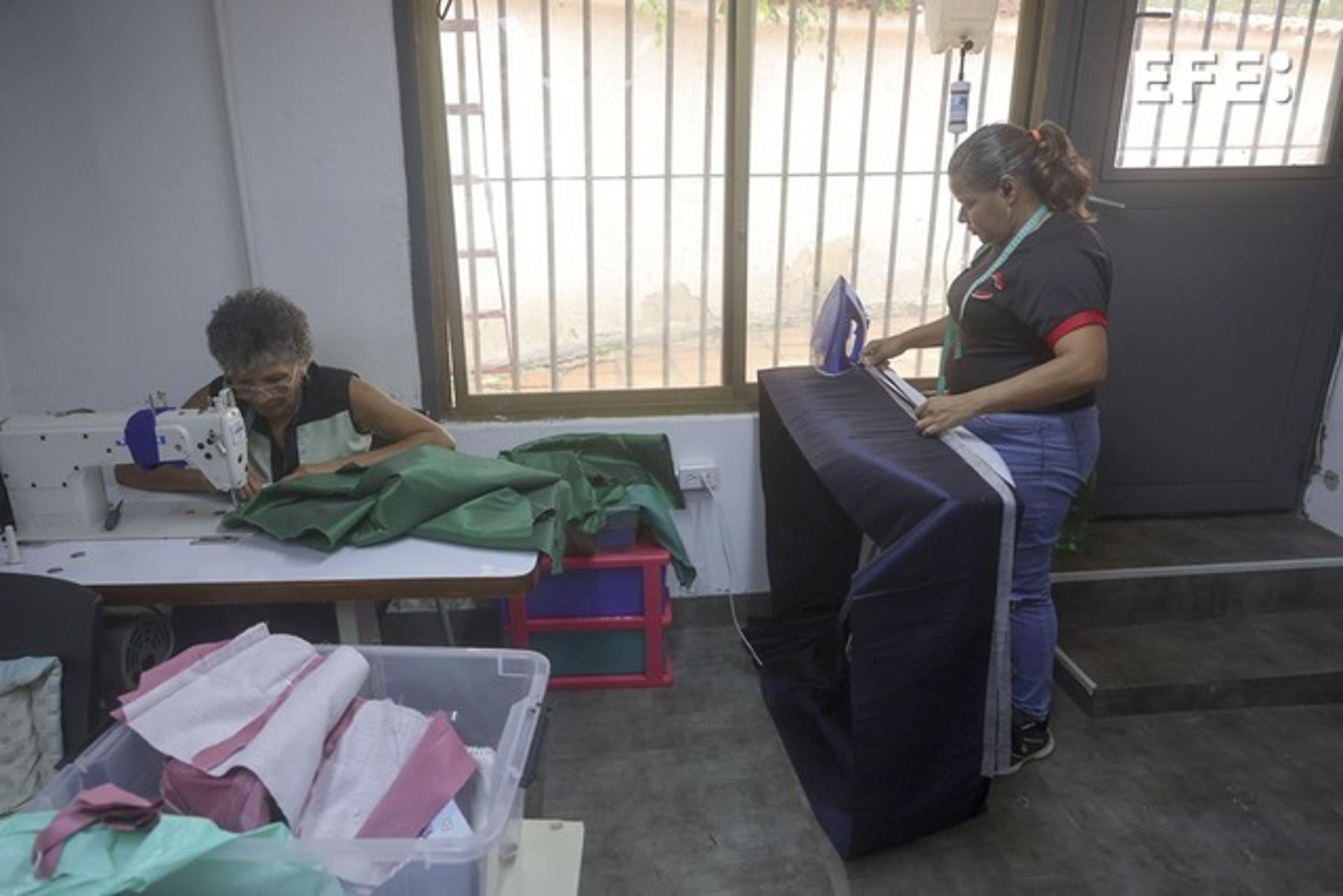 Personas trabajan confeccionando bolsas mortuorias en el taller de la diseñadora Estefanía Sánchez este lunes, en Caracas (Venezuela). EFE/ Miguel Gutierrez