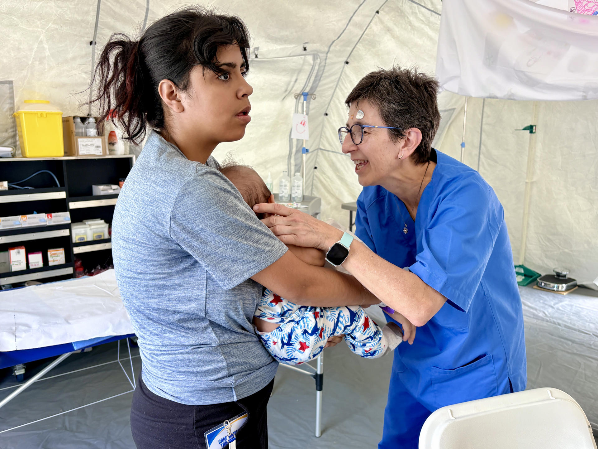 Génesis Tovar (i) sostiene a su bebé que es atendido por una médica en el hospital de campaña español en Caracas (Venezuela). EFE/ Jaime Olleros Sanchez