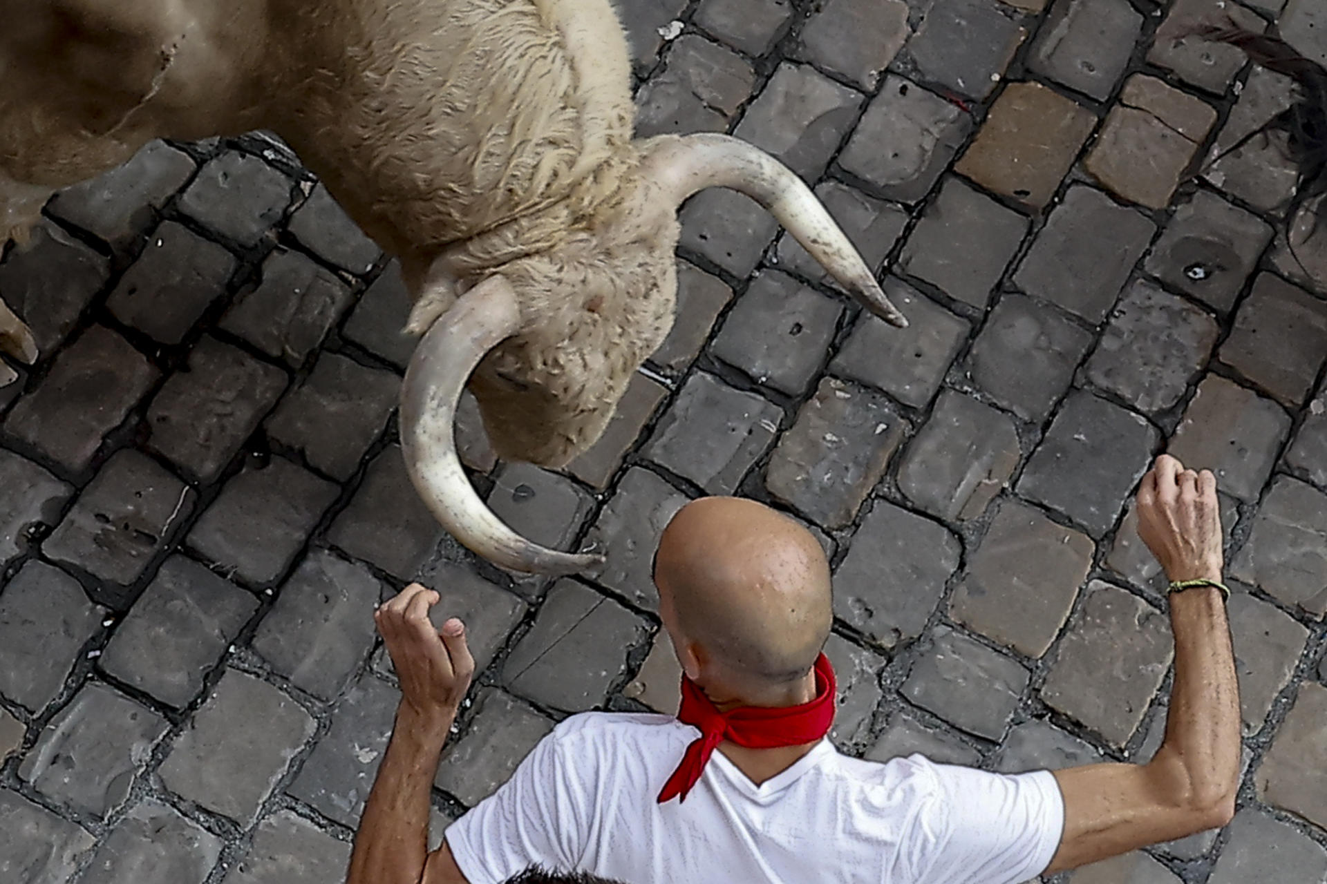 Un mozo ante uno de los toros de la ganadería Fuente Ymbro a su paso por la Plaza Consistorial en el primer encierro de los Sanfermines 2026, este martes en Pamplona. EFE/Villar López