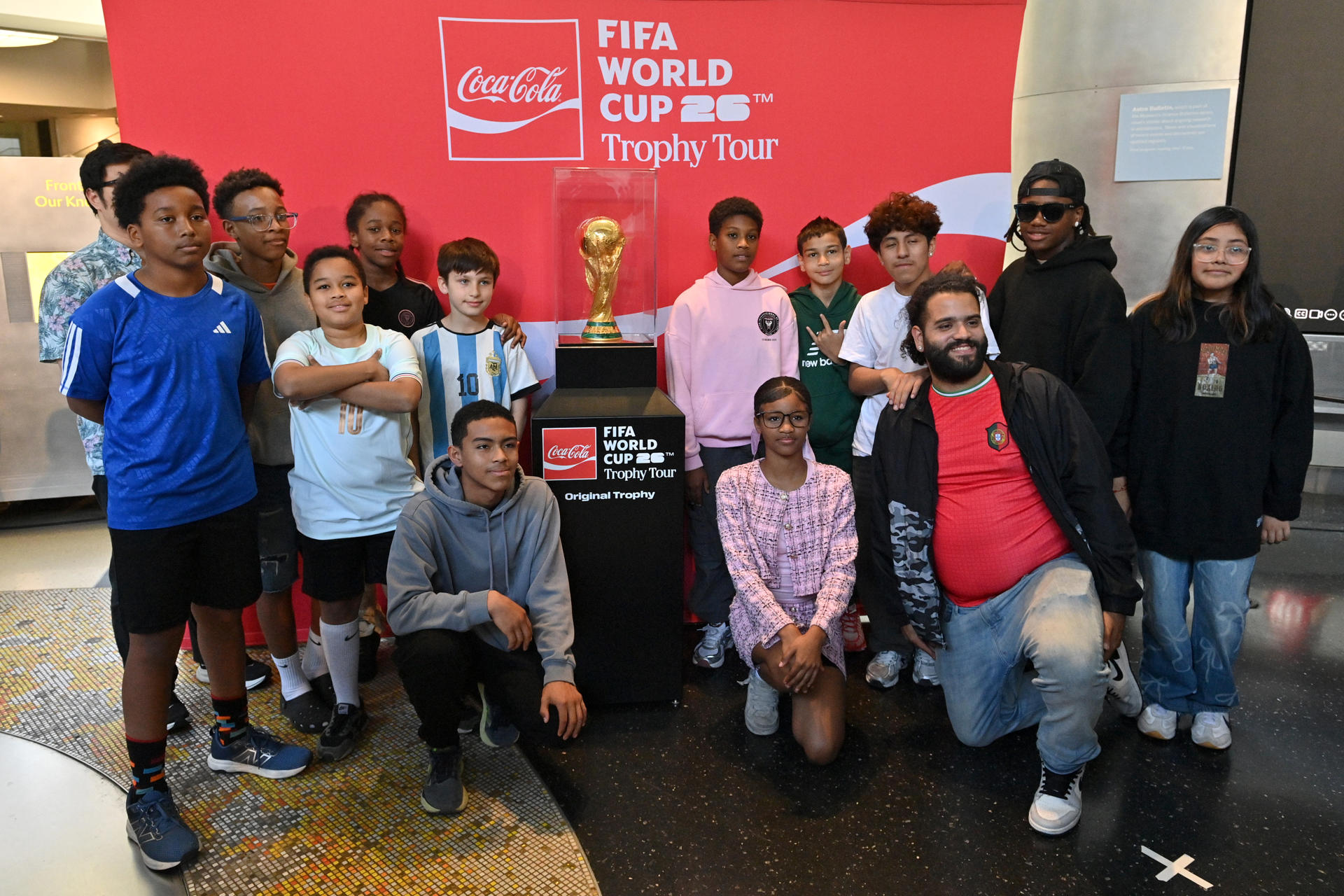 Jóvenes de los programas de City in the Community —la fundación del NYCFC— posan con el Trofeo de la Copa Mundial de la FIFA en el Museo Americano de Historia Natural el 2 de junio de 2026 en Nueva York (EE.UU.). EFE/ The Coca Cola Company
