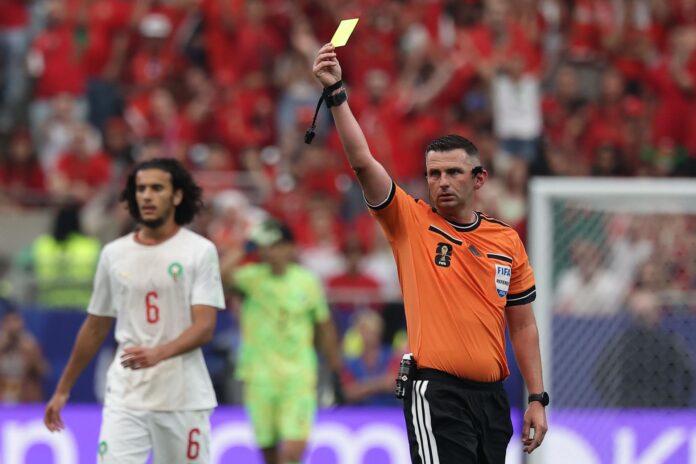 Fotografía del 4 de julio de 2026 en la que se observa al árbitro inglés Michael Oliver al mostrarle una tarjeta amarilla durante el partido de octavos de final del Mundial 2026 entre Canadá y Marruecos en Houston (EE.UU.). EFE/CHRISTOPHER NEUNDORF
